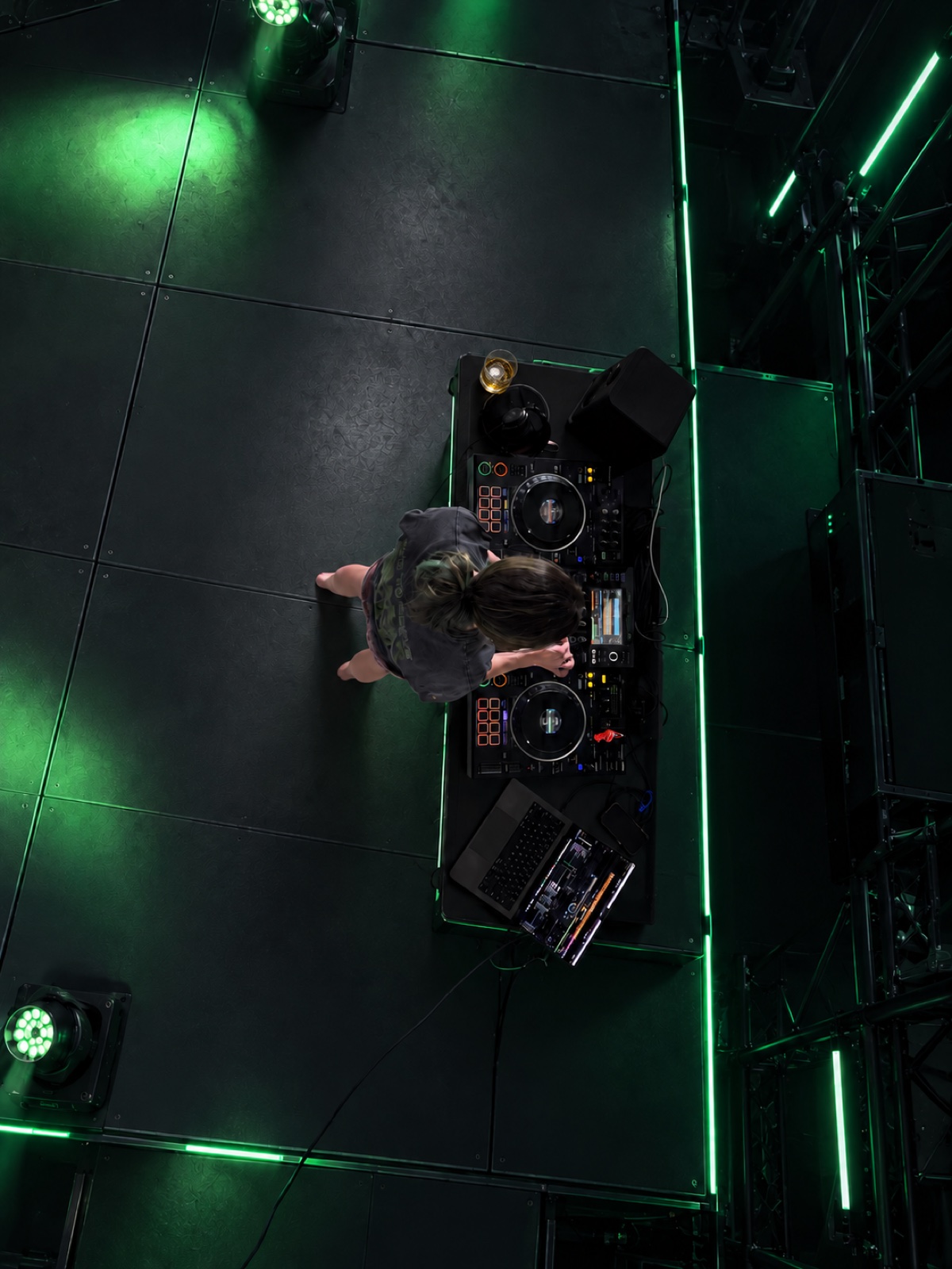 Brittany at the decks and laptop, viewed from above in an edited stage setting